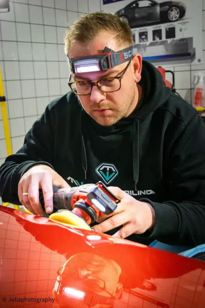 Detailer voert lakcorrectie uit op rode auto bij MW Car Detailing in Heerhugowaard