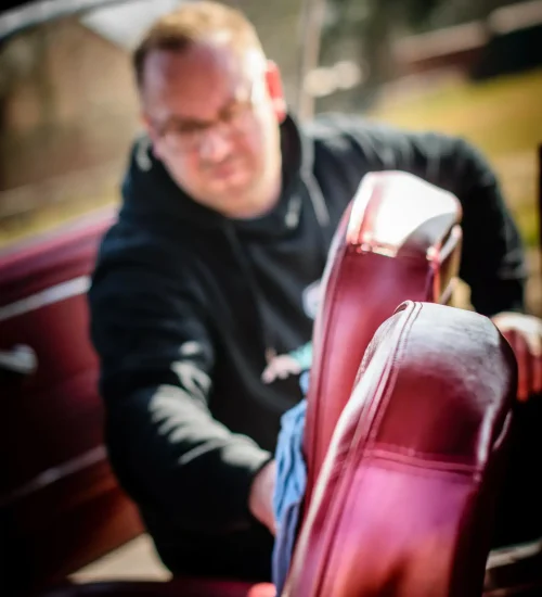 Detailer behandelt rode leren stoel bij MW Car Detailing in Heerhugowaard
