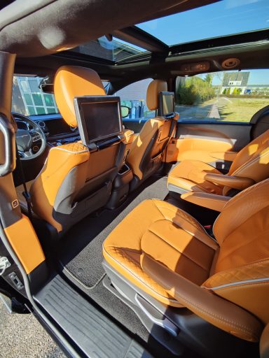 Interieur van een moderne auto met oranje leren bekleding en een scherm aan de achterzijde.